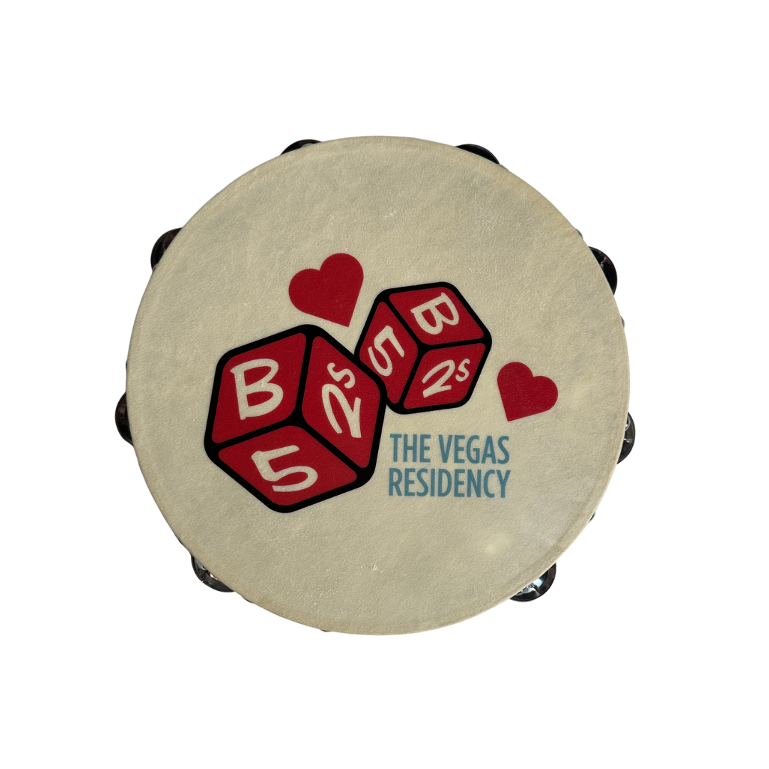Cream-colored dice tambourine with red dice and heart graphics and blue the vegas residency text b-52s official