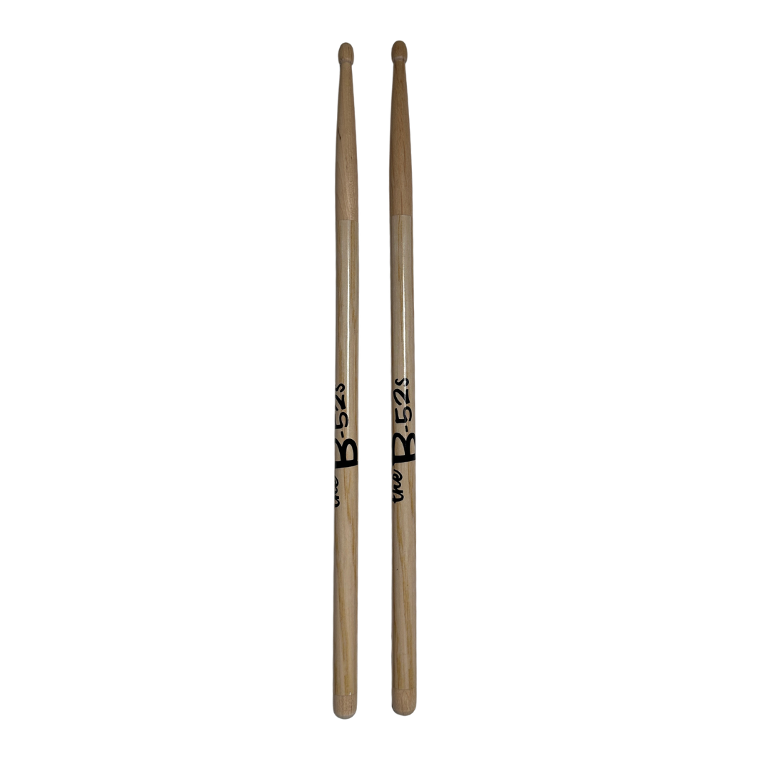 A pair of natural wood logo drumsticks with black b-52s branding from B-52s official merch